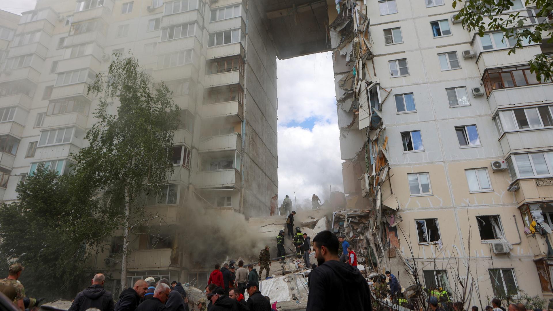 Russland, Belgorod: Menschen beseitigen Trümmer auf der Suche nach Überlebenden nach dem Einsturz eines Teils eines mehrstöckigen Wohnblocks als Folge eines ukrainischen Raketenangriffs.