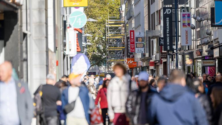 Passanten passieren diverse Geschäfte in der Kölner Fußgängerzone Hohe Straße am 23.10.2025. 