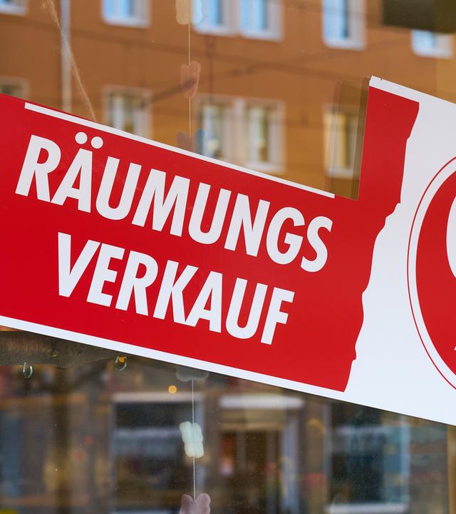 Schild mit Aufschrift "Räumungsverkauf" klebt an einer Ladenscheibe.