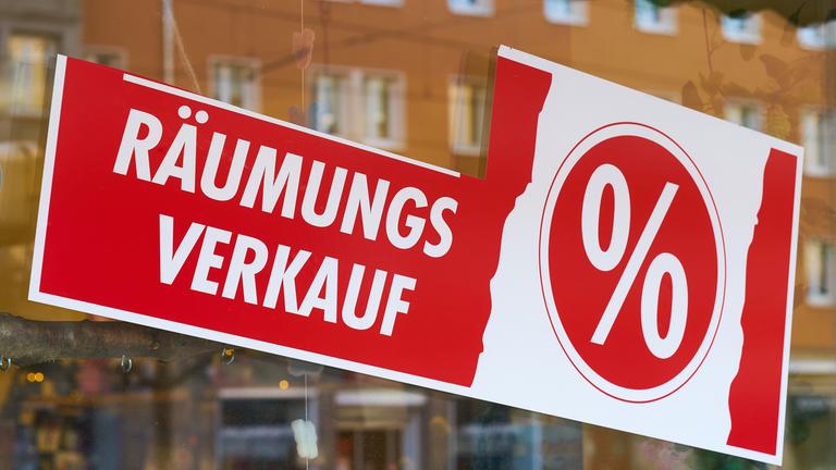 Schild mit Aufschrift "Räumungsverkauf" klebt an einer Ladenscheibe.
