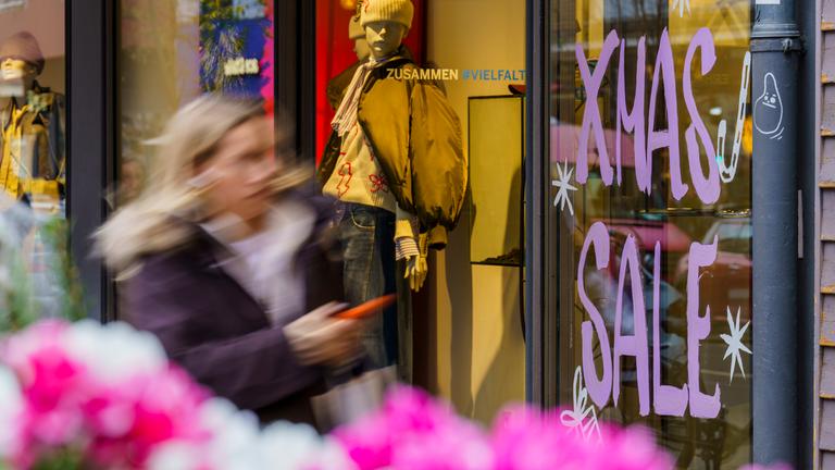 Eine Frau passiert ein Schaufenster, das mit Weihnachtsrabatten wirbt