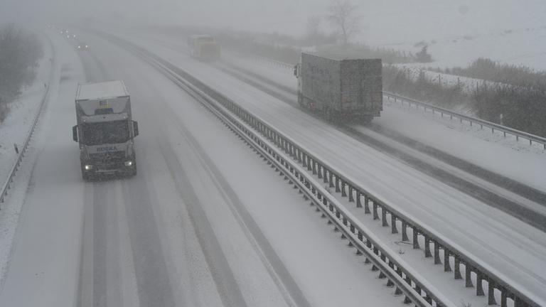 LKW sind auf der Autobahn 28 bei Brinkum bei Schneefall und schlechter Sicht unterwegs. 