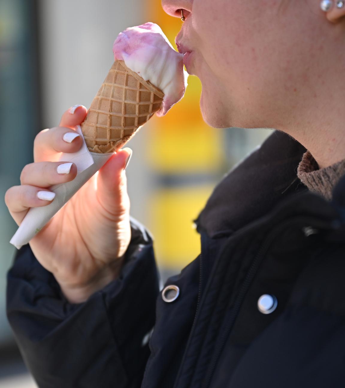 Eine Frau isst in ein Eis in der Stuttgarter Innenstadt.