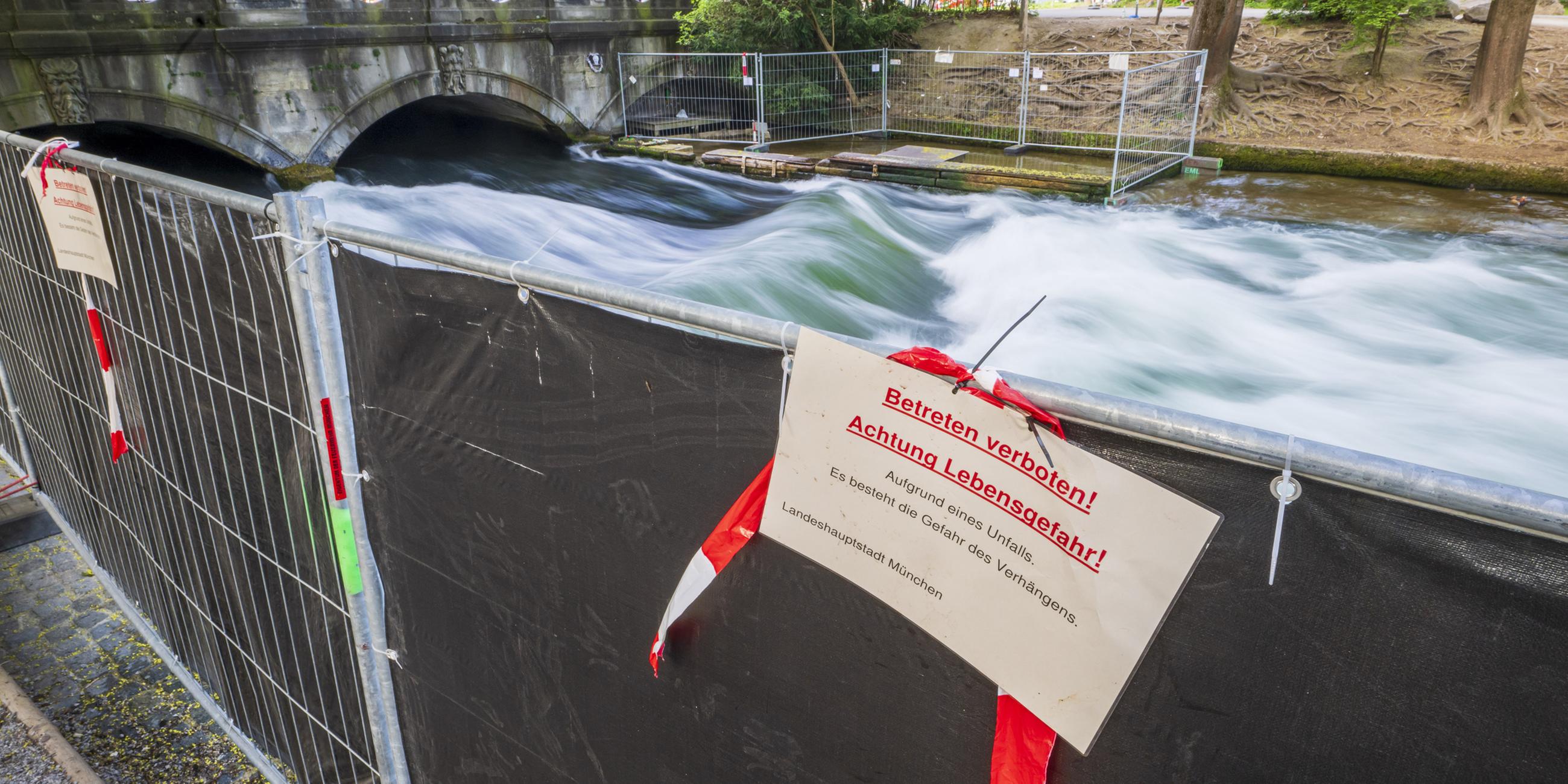 Ein Schild mit der Aufschrift "Betreten verboten! Achtung Lebensgefahr!" hängt an einer Absperrung vor der künstliche Welle am Eisbach.