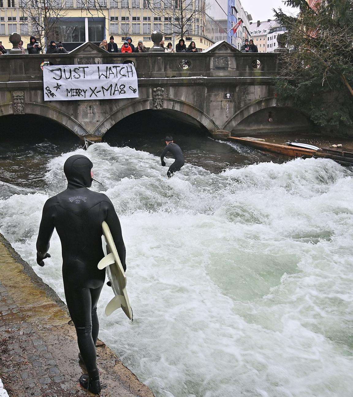 Ein Surfer in einem Neoprenanzug steht bereit, um am 26. Dezember 2025 auf der münchner Eisbachwelle zu surfen. 