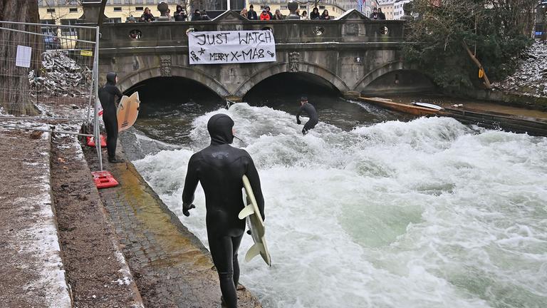 Ein Surfer in einem Neoprenanzug steht bereit, um am 26. Dezember 2025 auf der münchner Eisbachwelle zu surfen. 