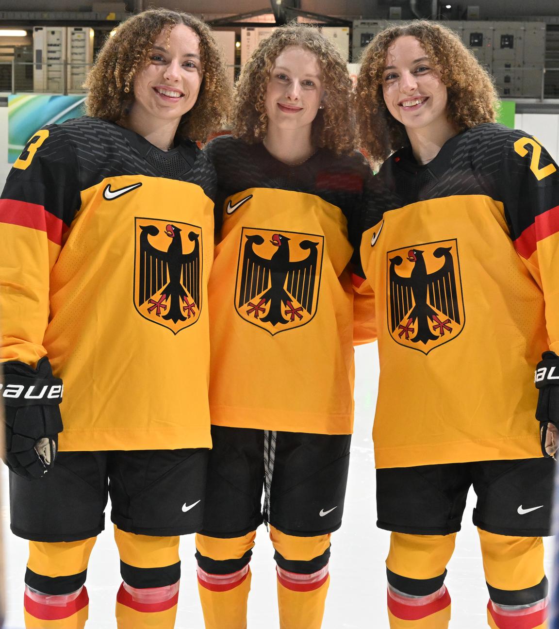 Die deutschen Eishockey-Spielerinnen Luisa Welcke, Svenja Voigt und Lilli Welcke (von links) posieren vor zwei Smartphones.
