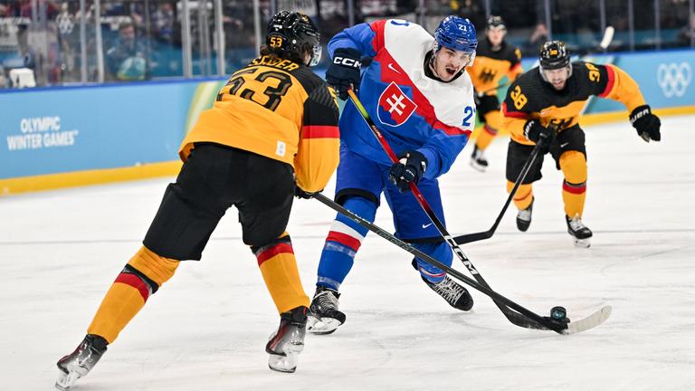 Der slowakische Eishockeyspieler Adam Ruzicka versucht im Zweikampf, den Puck mit dem Schläger an Deutschlands Nationalspieler Moritz Seider vorbeizulupfen