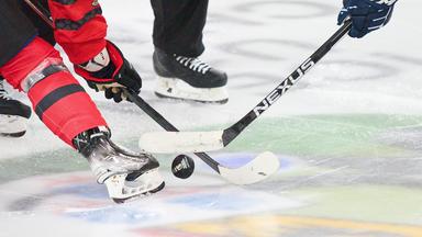 Zwei Eishockeyspielende kämpfen nach dem Einwurf um den Puck.