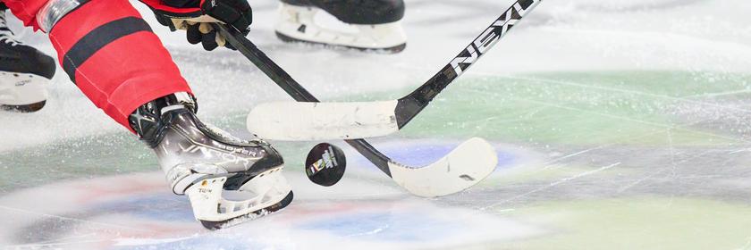 Zwei Eishockeyspielende kämpfen nach dem Einwurf um den Puck.