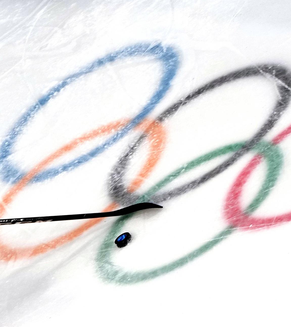 Die olympischen Ringe im Eis mit Puk und Schläger.