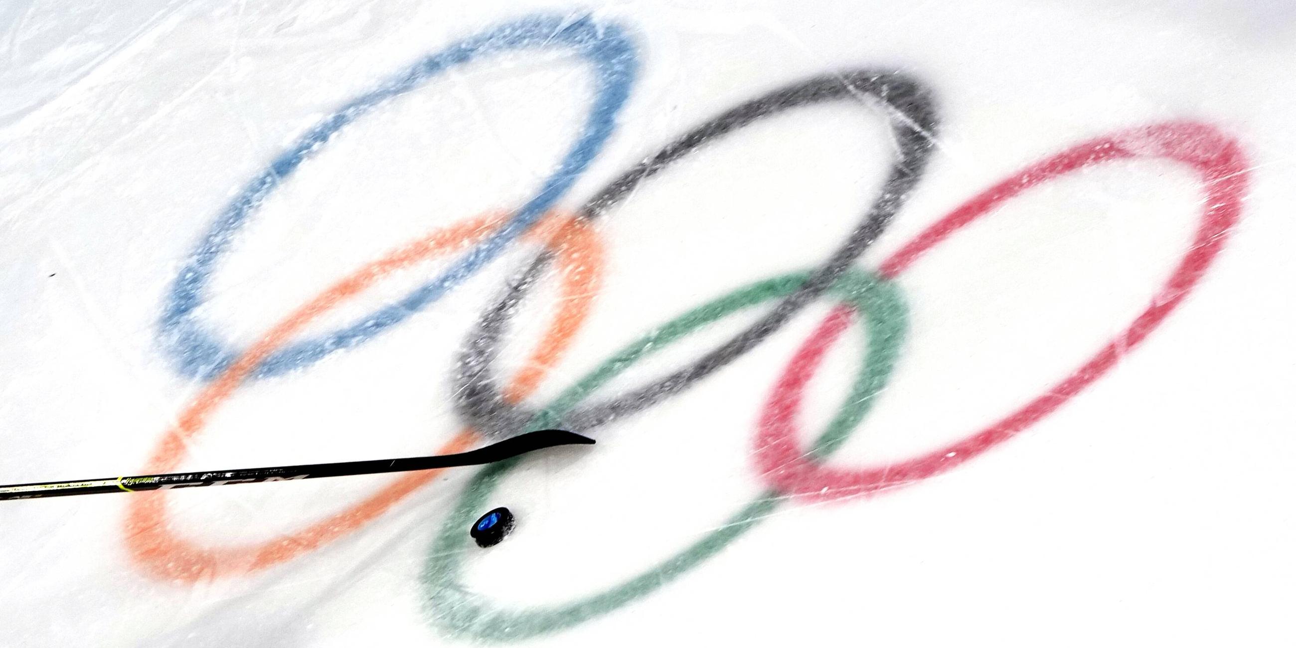 Die olympischen Ringe im Eis mit Puk und Schläger.