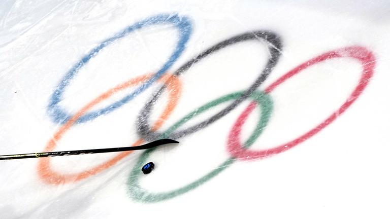 Die olympischen Ringe im Eis mit Puk und Schläger.