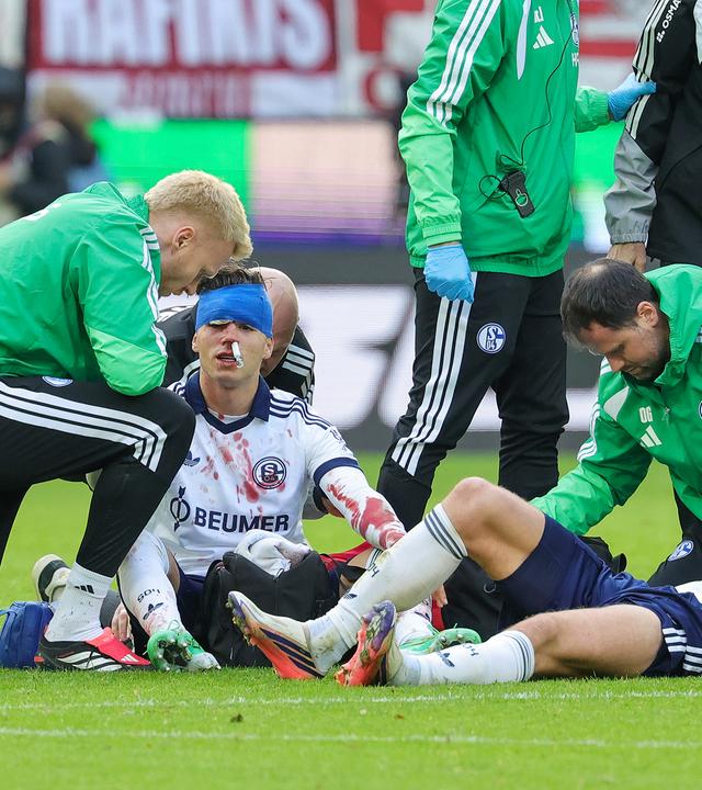 Die Schalker Soufiane El-Faouzi und Robin Gosens liegen nach einem Zusammenprall verletzt am Boden und werden behandelt
