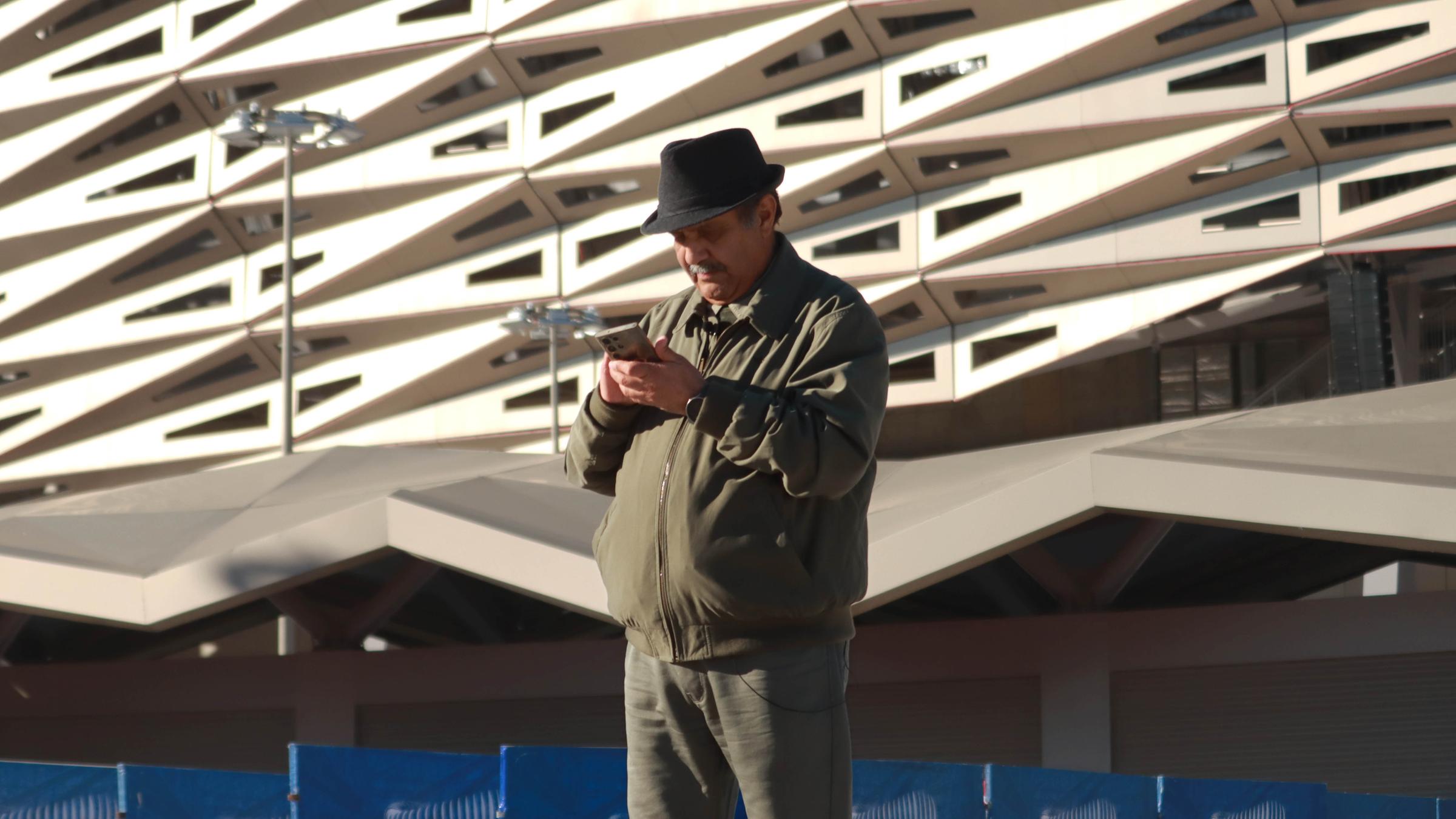 El Mouher vor einem Stadion am Smartphone