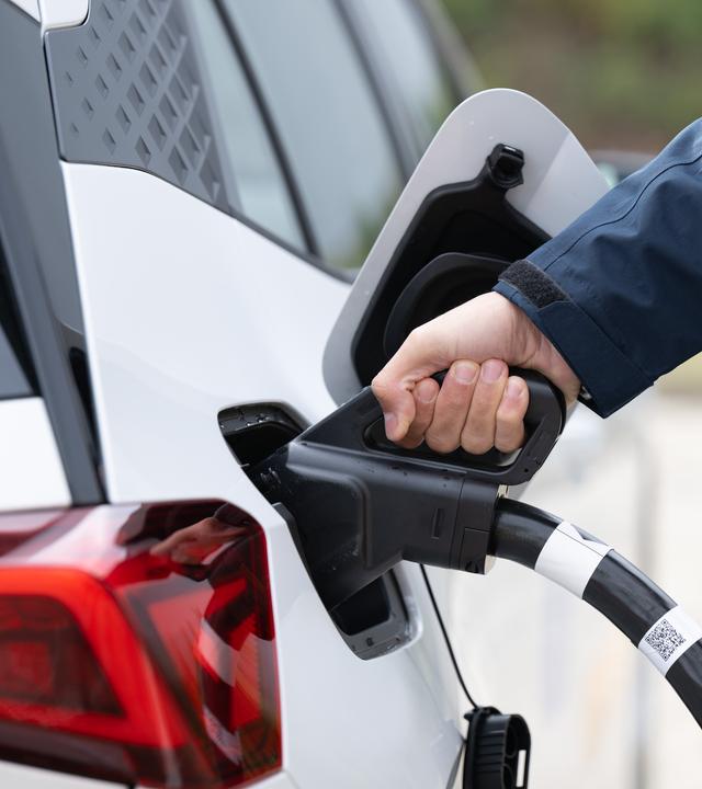 Sachsen, Klipphausen: Ein Mann steckt ein Ladekabel in den Tankstutzen eines Elektroautos