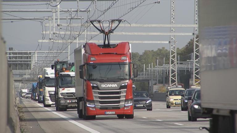 LKW fährt mit Oberleitung auf Elektroautobahn.