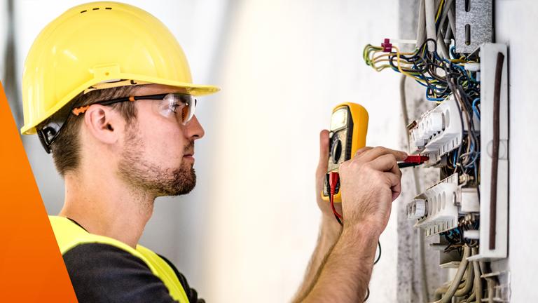 Mann mit Helm repariert einen Stromkreis