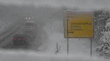 Autos sind auf einer verschneiten Straße bei Oberhof unterwegs. In der Stadt im Thüringer Wald schneit es ergiebig