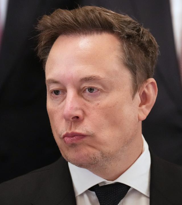 n: Elon Musk hört zu, während US-Präsident Trump im East Room des Weißen Hauses in Washington bei einem Treffen mit Führungskräften von KI-Unternehmen spricht.