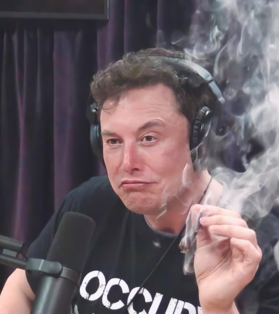 Elon Musk, mit schwarzem T-Shirt mit weißer Aufschrift, sitzt während eines Interviews im Jahr 2018 vor einem Mikrophon und hält in der linken Hand einen Joint, der qualmt.