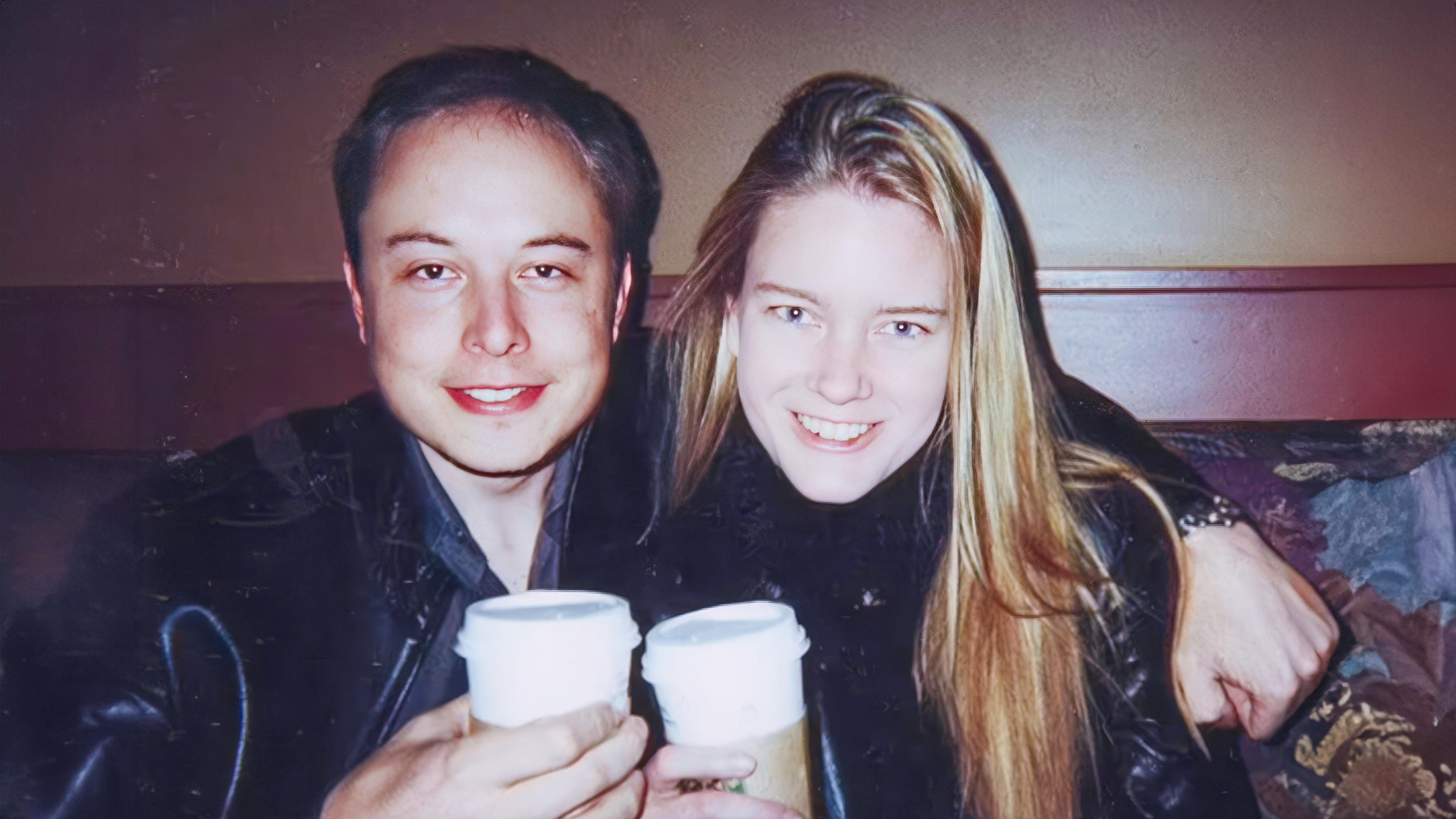 Elon Musk und Justine Wilson sitzen nebeneinander und lächeln in die Kamera. Elon Musk hat seinen Arm um Justine Wilson gelegt und sie halten beide Kaffeebecher in den Händen.