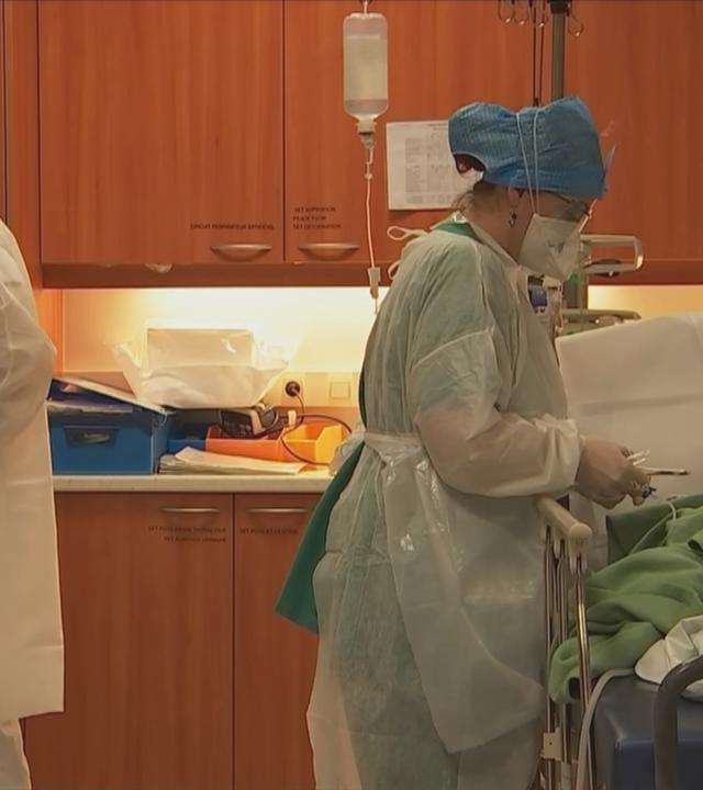 Zwei Mitarbeiter mit Schutzkleidung und ein Patient in einem Krankenhaus im Elsass