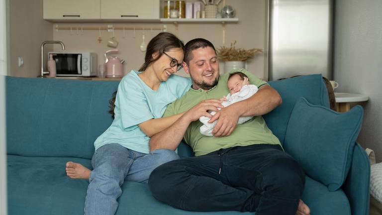 Mutter und Vater umarmen ihr Baby auf dem Sofa zu Hause.