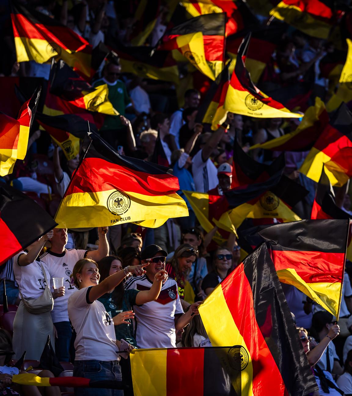 Deutsche Fans jubeln und schwenken Fahnen bei der Fußball EM der Frauen.
