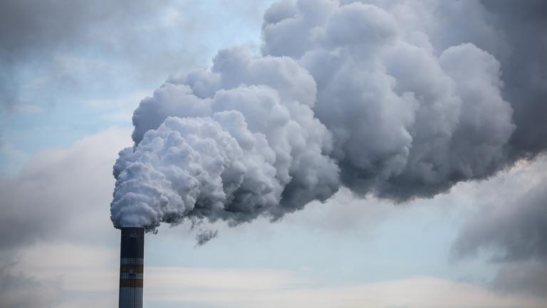 Qualm steigt aus Schornstein eines Braunkohlekraftwerks.