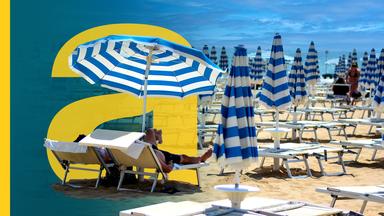 Viele Reihen von Strandliegen mit blau-weißen Schirmen