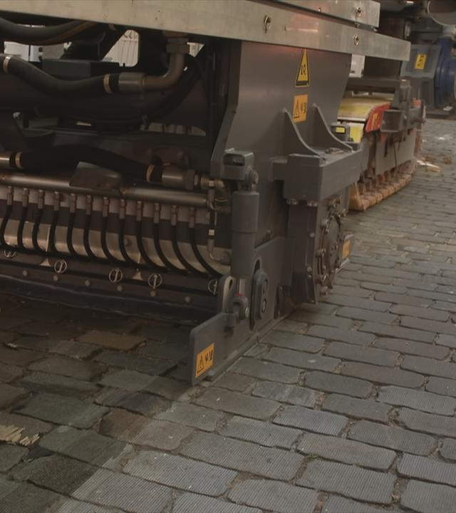 Eine große Maschine schleift Kopfsteinpflaster ab