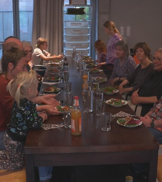 Mehrere Leute sitzen mit Kindern am Tisch.