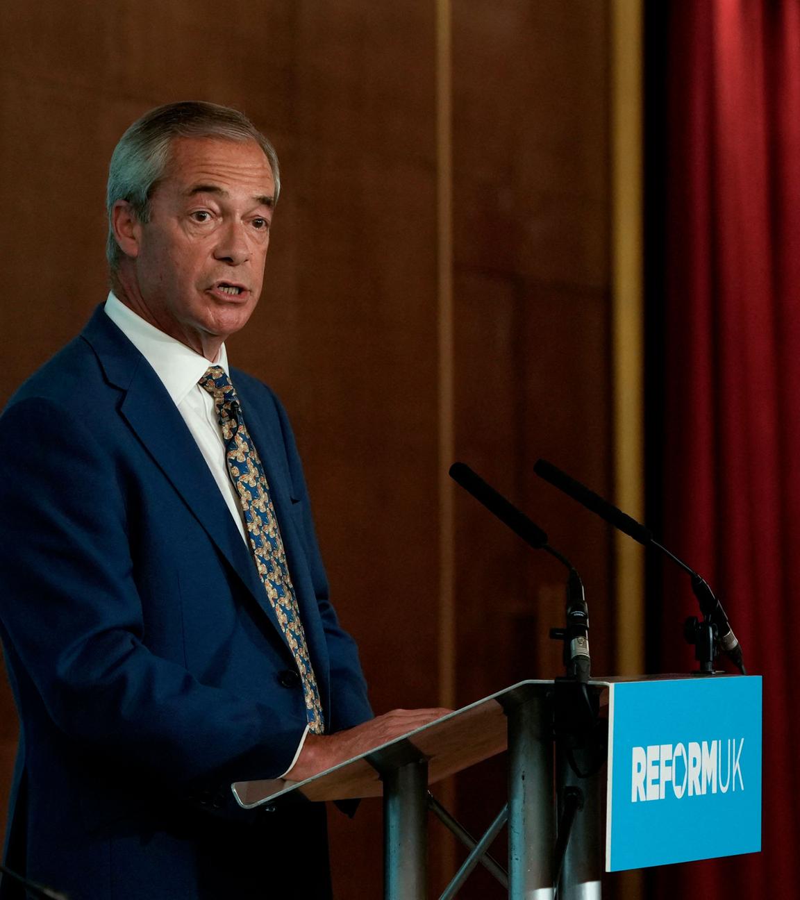 Nigel Farage steht hinter einem Rednerpult.