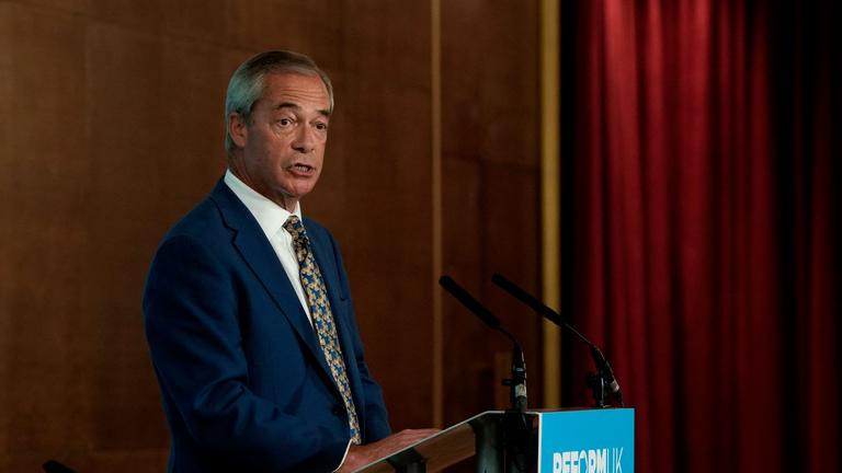 Nigel Farage steht hinter einem Rednerpult.