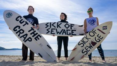 drei Surfer die gegen Abwasser protestieren