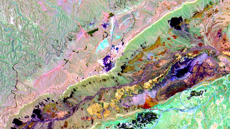 Satellitenaufnahme eines Kraters. Verschiedene Gesteinsarten sind unterschielich gefärbt.