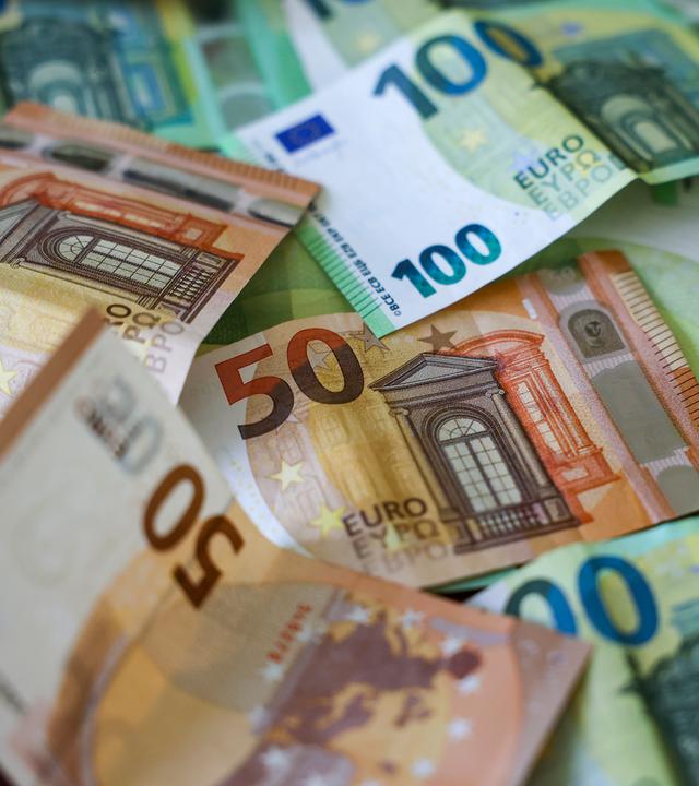 Mehrere Hunderter und Fünfziger Euro Geldscheine liegen auf einem Tisch.