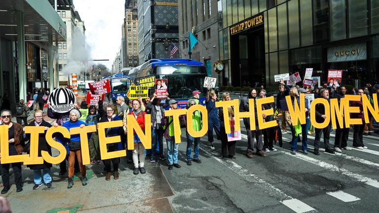 Protestierende halten in New York gelbe Buchstaben in die Höhe, die zusammen den Satz "Listen to the women" ergeben.