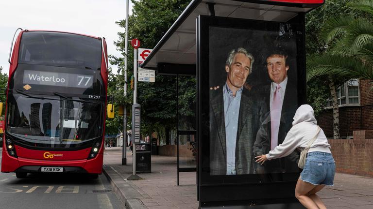 Großbritannien, London: Aktivisten hängen ein Plakat, das US-Präsident Donald Trump und Jeffrey Epstein zeigt, an einer Bushaltestelle in der Nähe der US-Botschaft auf.