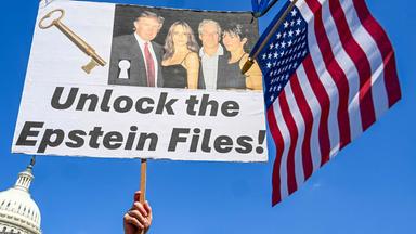 Ein Mann hält ein Schild mit der Aufschrift "Unlock the Epstein Files" hoch.