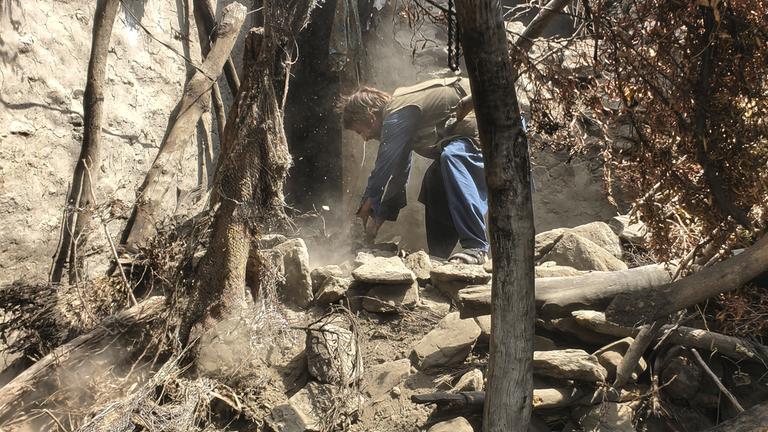 Ein Mann versucht, die Trümmer eines eingestürzten Hauses zu beseitigen.