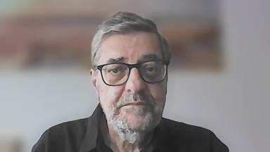 Latein-Amerika Experte Günther Maihold in einem schwarzen Hemd und einer schwarzen Brille. Man sieht ihn ab den Schultern aufwärts. Der Hintergrund ist unscharf gestellt.