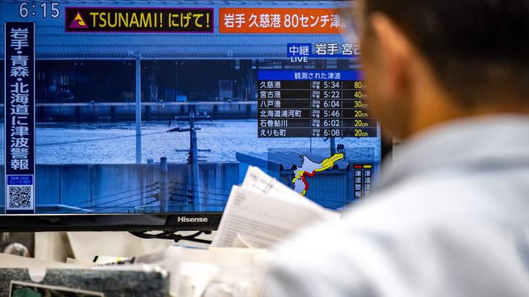 Eine Warnmeldung auf einem Bildschirm mit Live-Bildern von NHK, die nach einem Erdbeben im Norden Japans am 20.04.2026 in Tokio eine Tsunami-Warnung auslöste. 