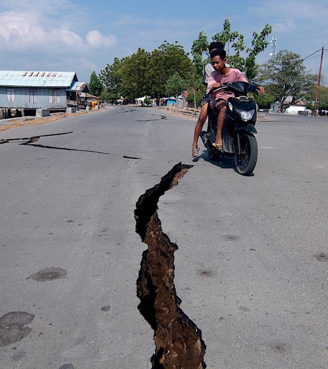 Ein Motorradfahrer fährt an einem Riss in der Straße vorbei, nachdem sich am 15. August 2026 in Mbay (Regierungsbezirk Nagekeo, Provinz Ost-Nusa Tenggara, Indonesien) ein Erdbeben der Stärke 7,7 ereignet hat. 