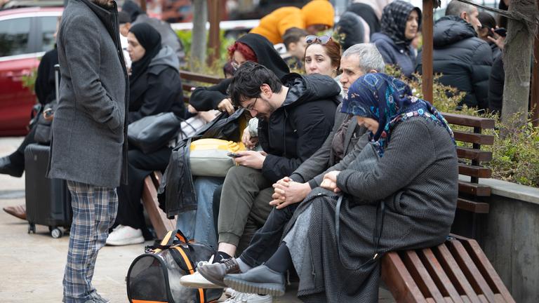 Menschen mit ihren Habseligkeiten sitzen nach einem starken Erdbeben in Istanbul in einem Park.