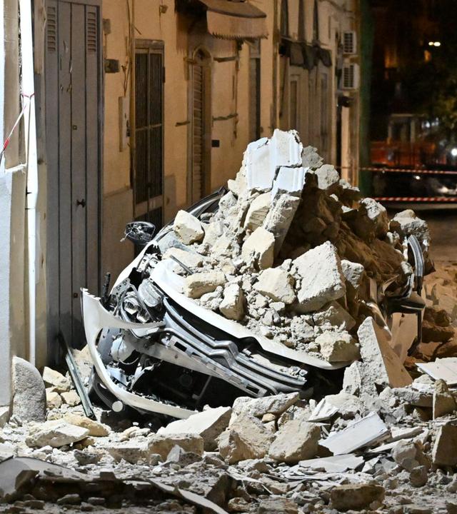 Steine und Trümmerteile liegen nach einem Erdbeben bei Neapel auf einem Auto, das dadurch zerstört ist.