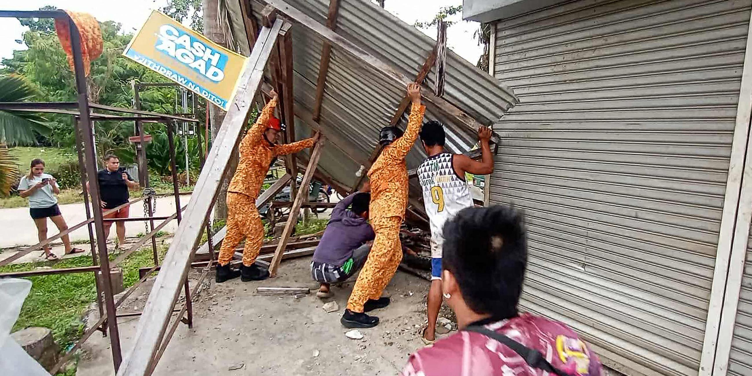 Mitglieder des Amts für Brandschutz (Bureau of Fire Protection) und Anwohner reparieren eine beschädigte Zimmerdecke in der Stadt Baganga, Provinz Davao Oriental auf der südlichen Insel Mindanao, nachdem am 10. Oktober 2025 ein starkes Erdbeben der Stärke 7,4 den Süden der Philippinen erschüttert hat.