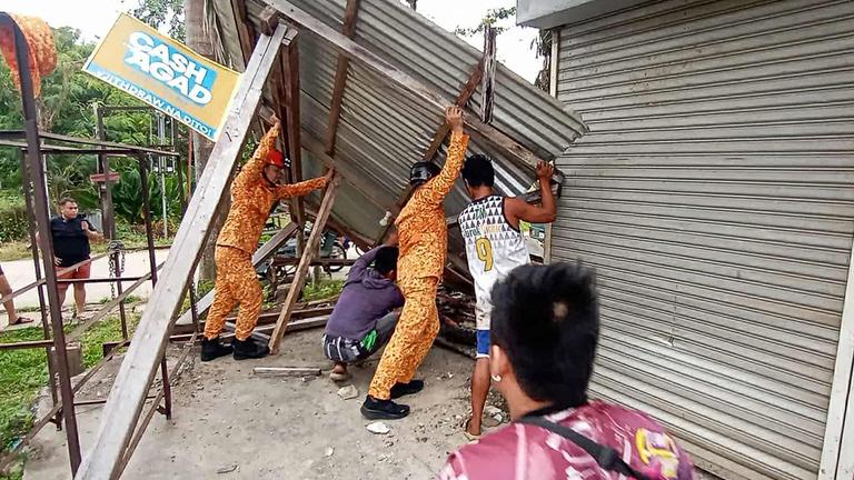Mitglieder des Amts für Brandschutz (Bureau of Fire Protection) und Anwohner reparieren eine beschädigte Zimmerdecke in der Stadt Baganga, Provinz Davao Oriental auf der südlichen Insel Mindanao, nachdem am 10. Oktober 2025 ein starkes Erdbeben der Stärke 7,4 den Süden der Philippinen erschüttert hat.