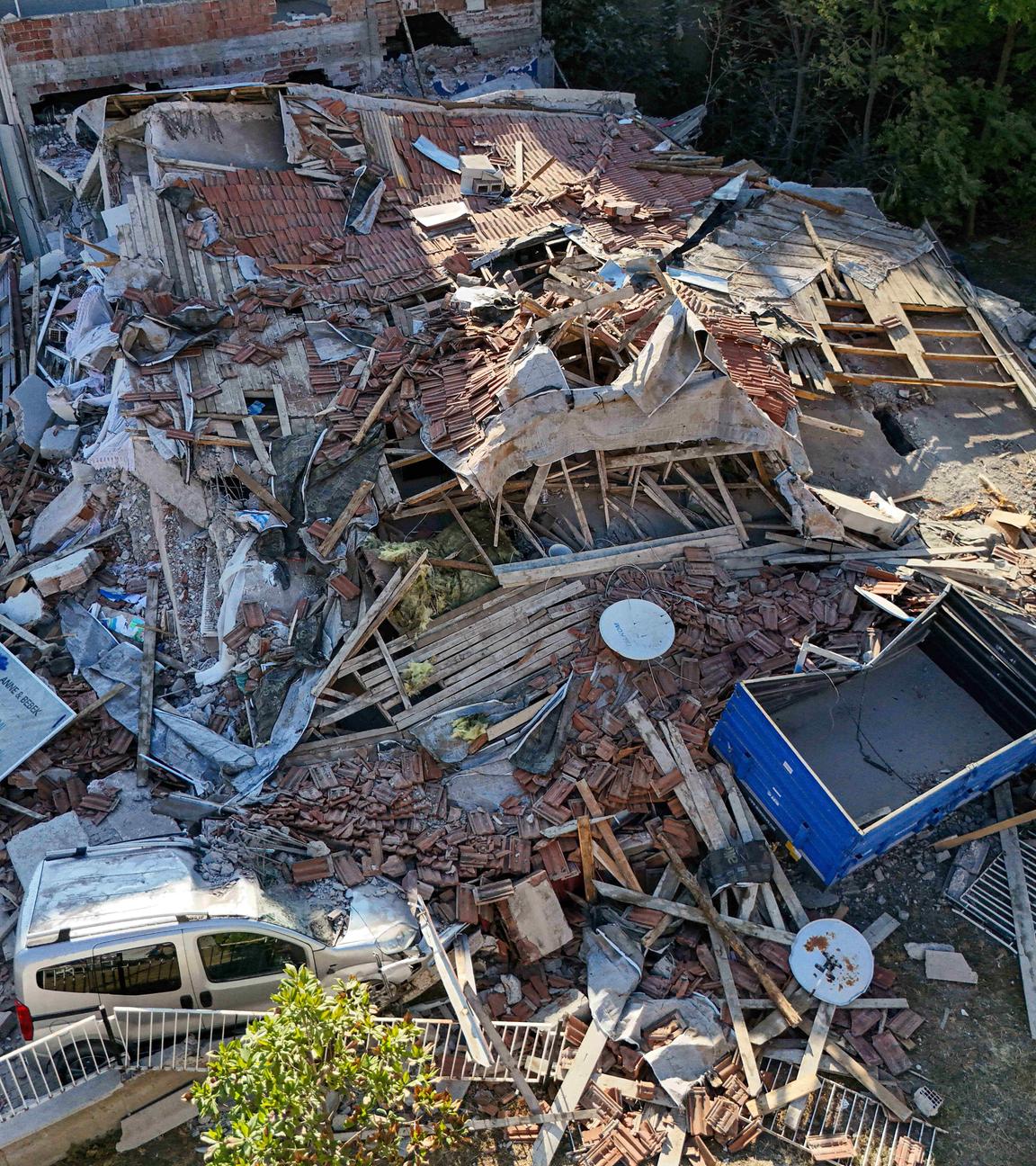 Ein eingestürztes Haus. Teile des Gebäudes liegen auf einem Auto. Das Haus ist vollständig zerstört.